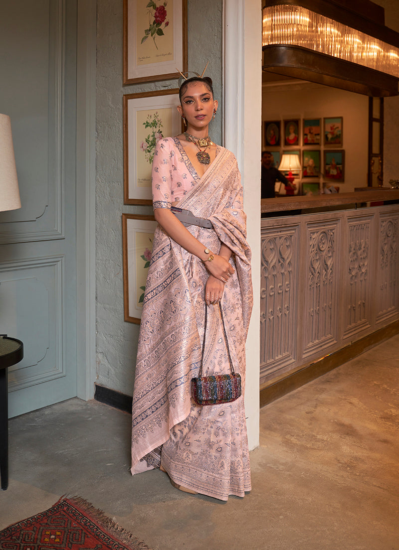 A close-up view of a baby pink traditional silk saree featuring intricate ethnic weaving work and a matching blouse.