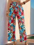 Woman wearing vibrant floral printed wide leg pants with a tied waist and pockets