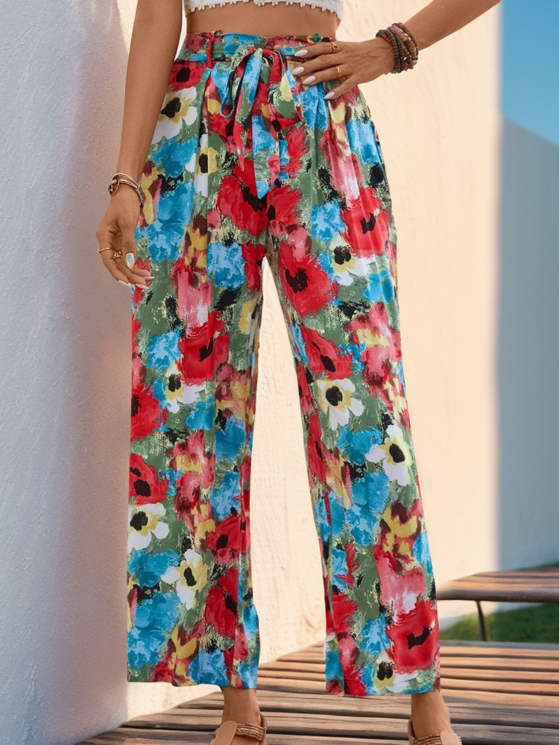 Woman wearing vibrant floral printed wide leg pants with a tied waist and pockets