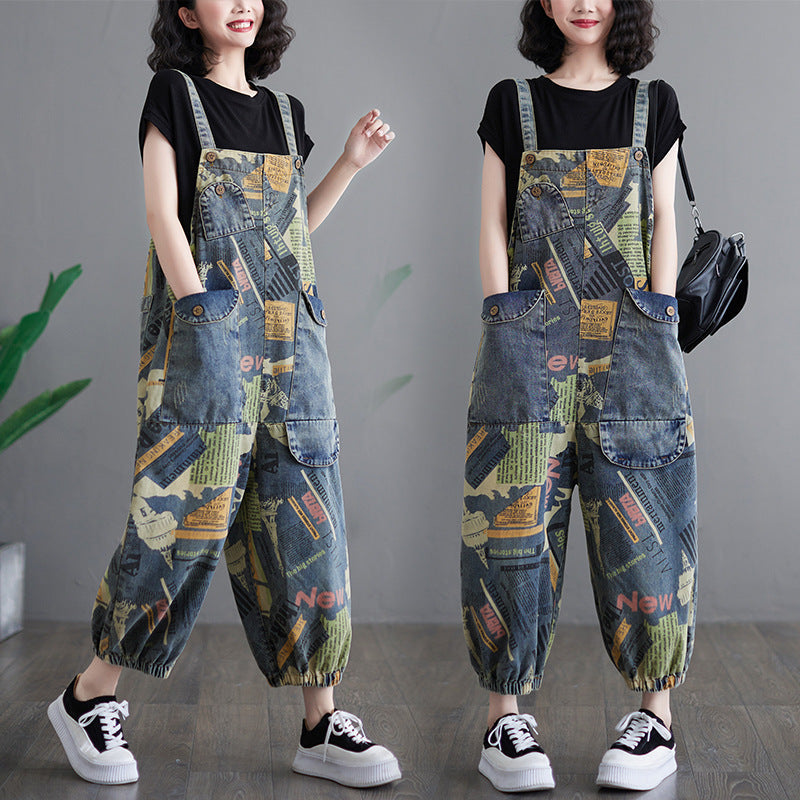 A model wears retro-printed denim overalls featuring a unique artistic print in blue, olive green, and yellow, adjustable straps, and multiple pockets, styled with a black t-shirt and white sneakers.