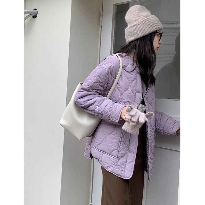 Woman wearing a loose-fit quilted single-breasted cotton baseball coat in lilac and cream, styled for autumn and winter.