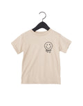 X-Eye smiley graphic tee available in beige or black, perfect for streetwear outfits.