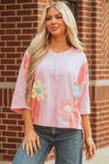 A woman wearing a pink oversized t-shirt with flower patches and exposed seam details.