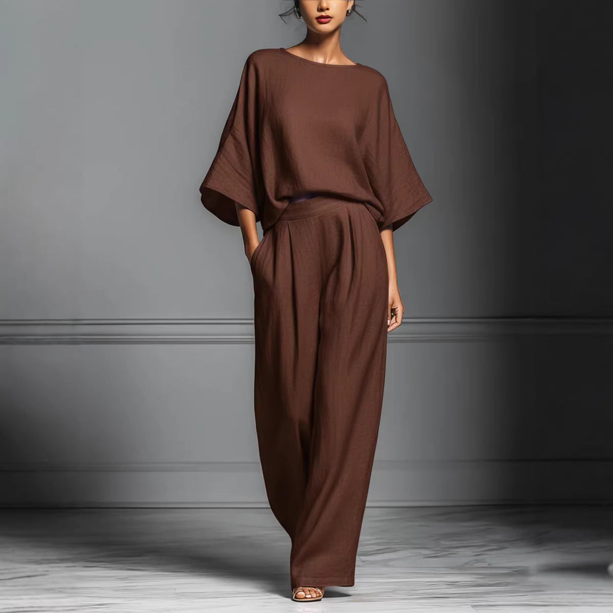 A woman wearing a beige linen two-piece set with flared sleeves and wide-leg trousers.