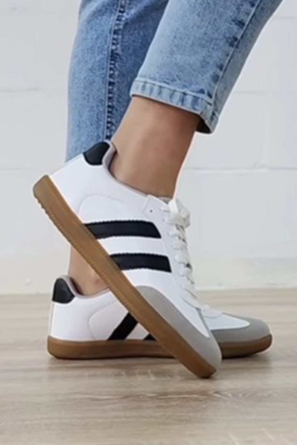 Close-up of Willa Striped Lace-up Flat Sneakers featuring a gum sole and striped suede and PU leather design on a model.
