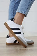 Close-up of Willa Striped Lace-up Flat Sneakers featuring a gum sole and striped suede and PU leather design on a model.