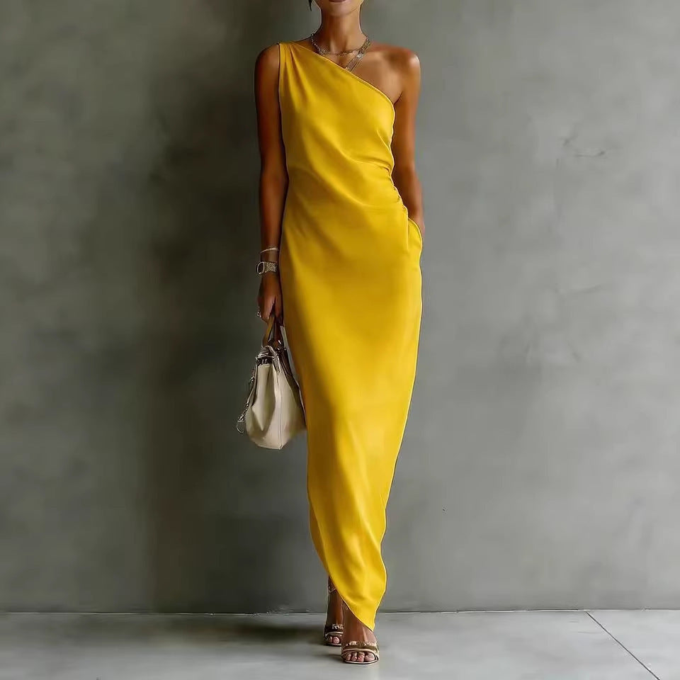 A woman wearing a sleek, yellow satin one-shoulder maxi dress in a slim-fit cut.