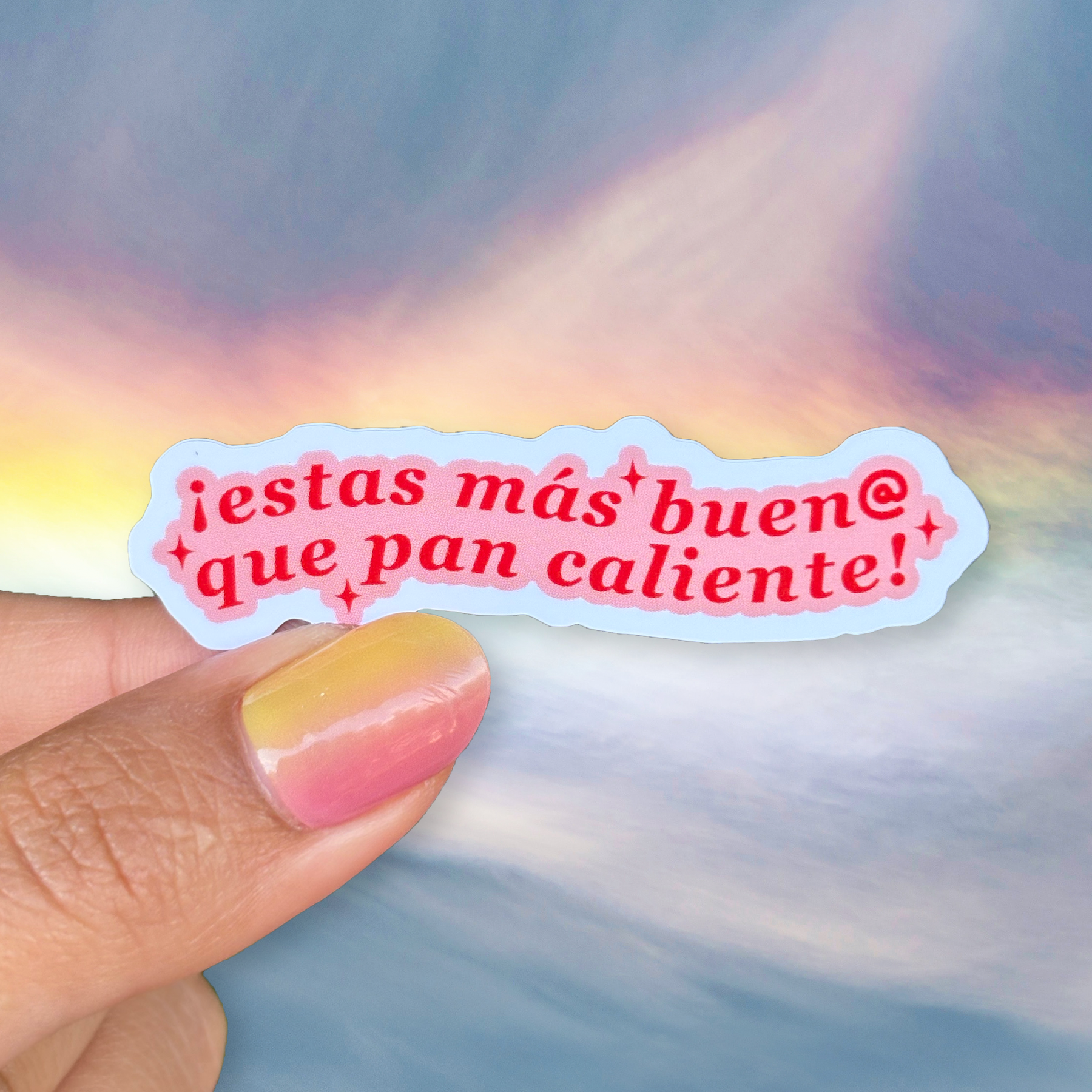 Sticker with Spanish text held by a hand against a colorful background