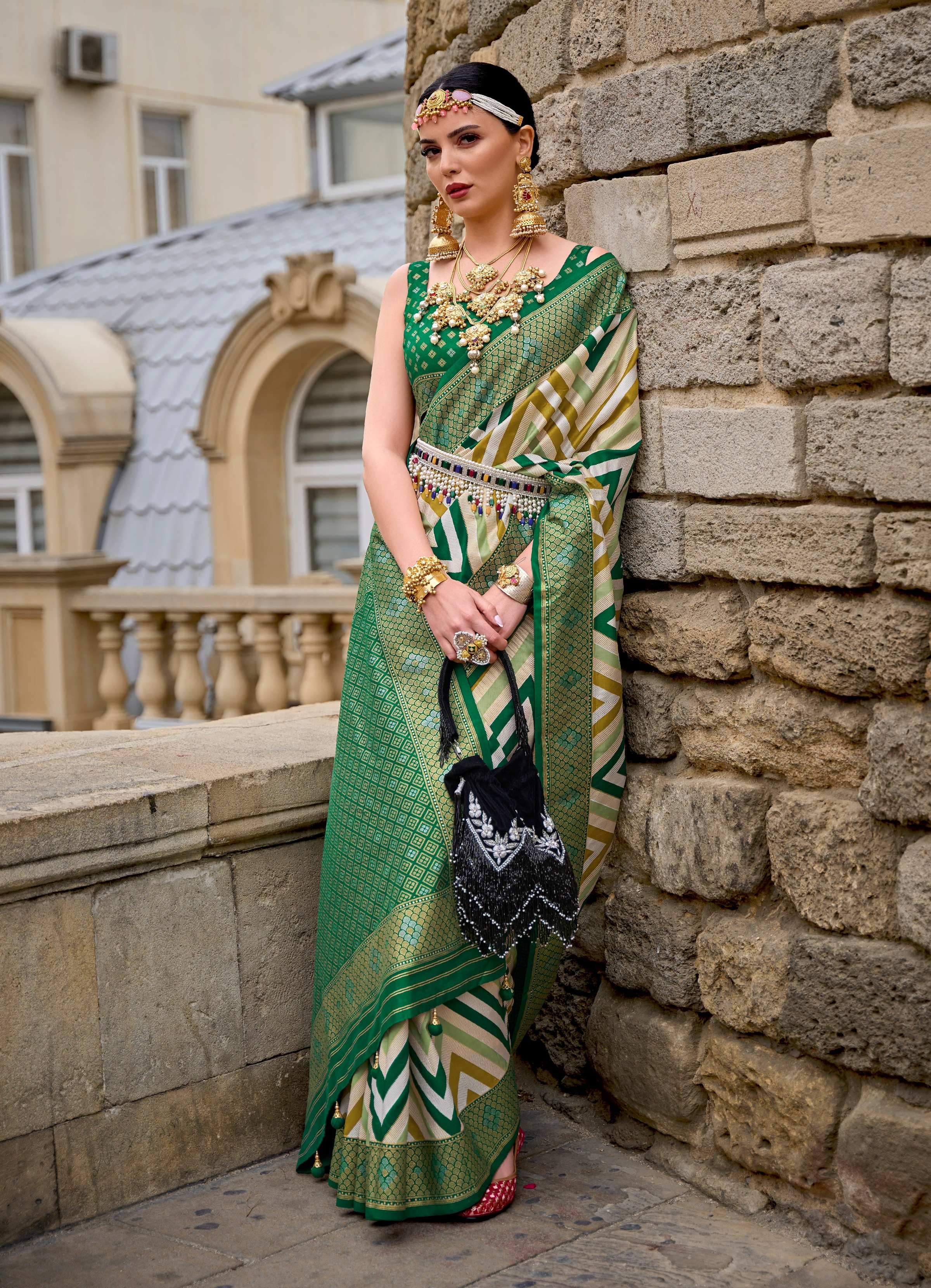 A green silk saree featuring a geometric border pattern and matching blouse piece.