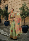 A soft light green silk saree featuring intricate woven patterns for traditional occasions
