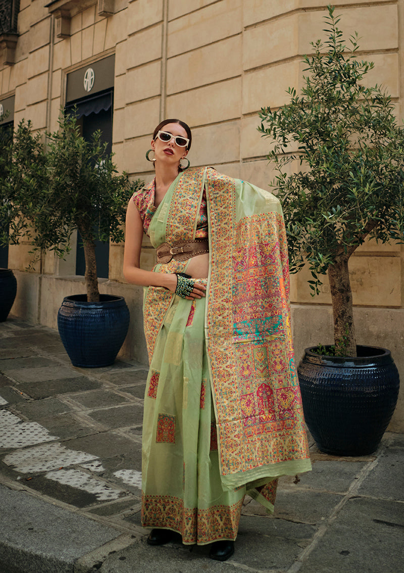 A soft light green silk saree featuring intricate woven patterns for traditional occasions