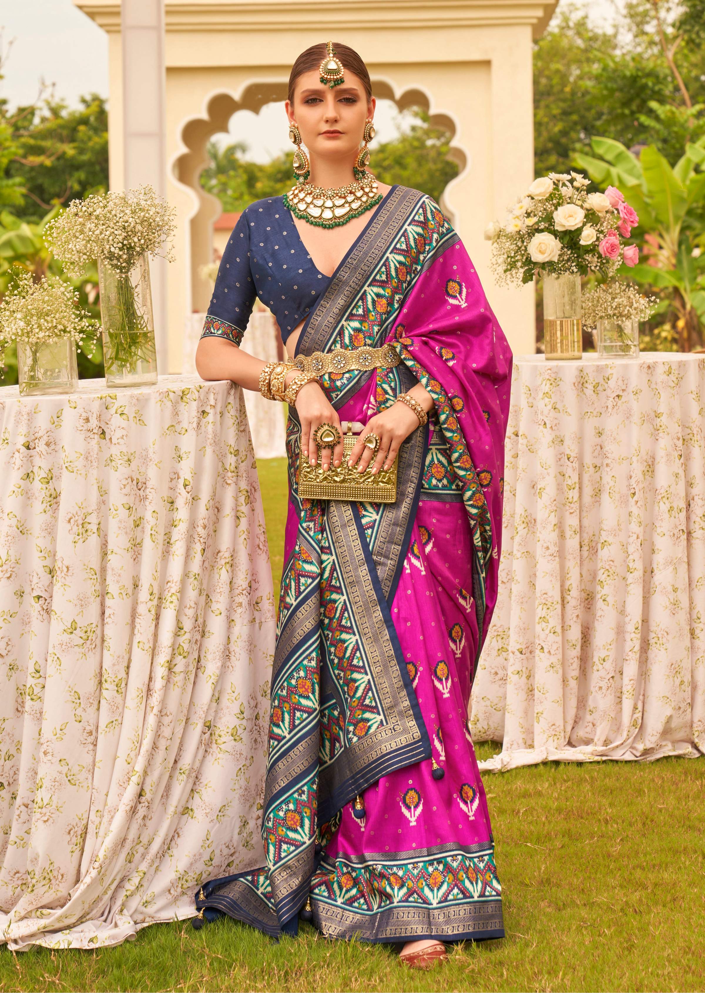 Elegant magenta silk saree featuring traditional Patola prints and a matching blouse piece.
