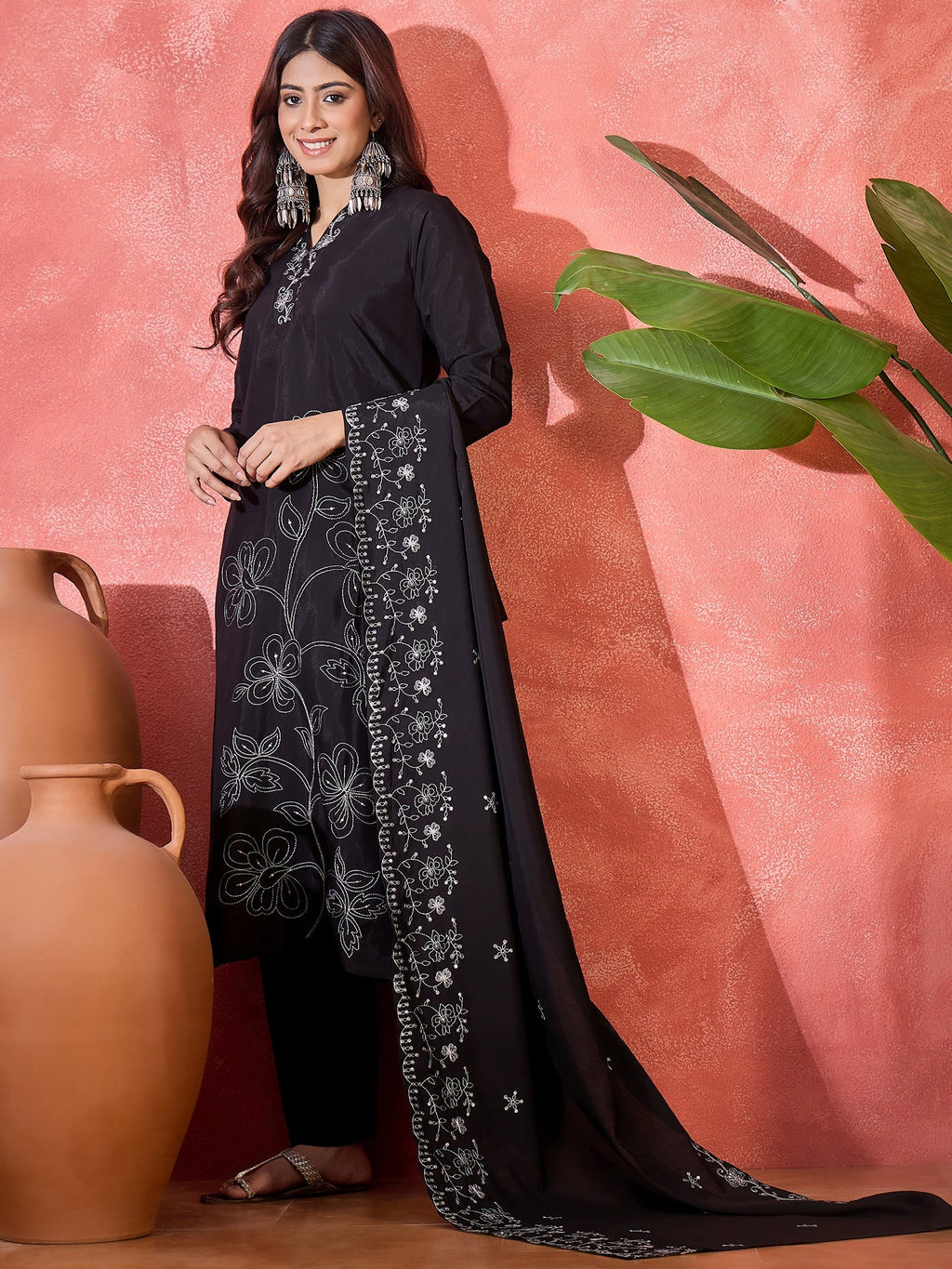 Woman wearing a black silk kurta set with intricate silver floral embroidery on the front panel and hemline