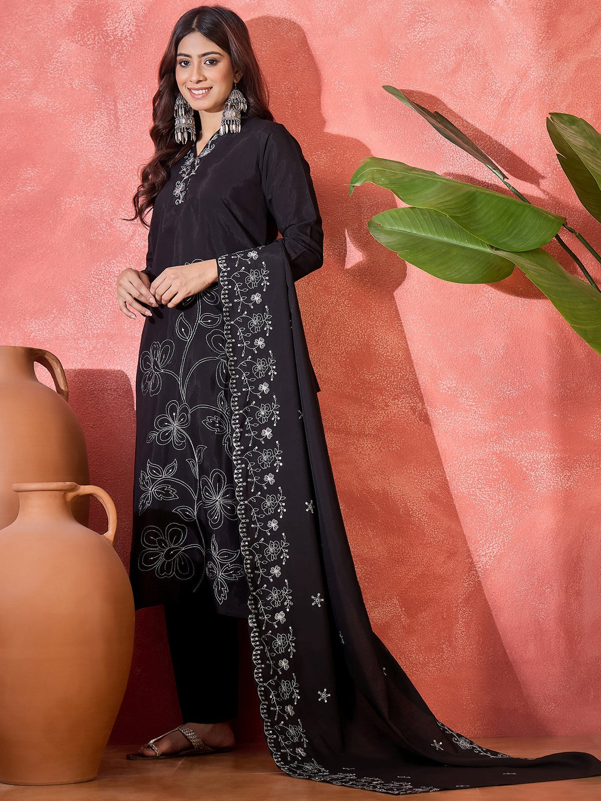 Woman wearing a black silk kurta set with intricate silver floral embroidery on the front panel and hemline