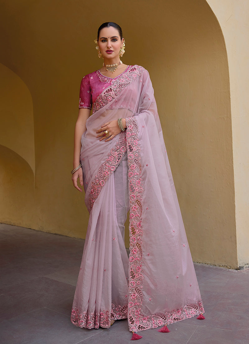 A toddler girl wearing a baby pink organza silk party saree with heavy zari and sequin embroidery.