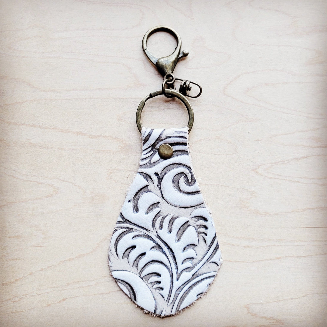 Sandy white floral embossed leather keychain with rustic antique metal clip.