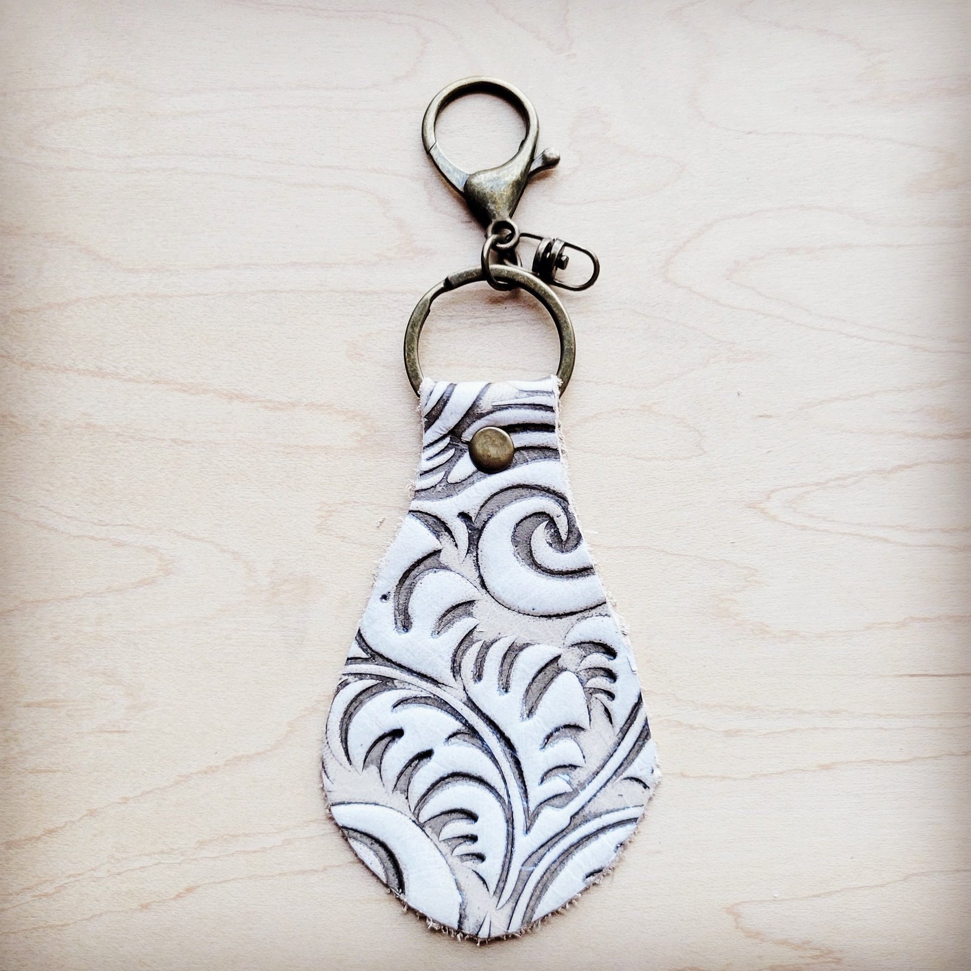 Sandy white floral embossed leather keychain with rustic antique metal clip.