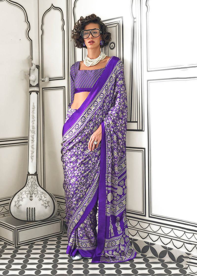 Woman wearing a royal blue satin crepe saree with abstract print patterns