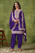 Woman wearing a violet Chanderi silk salwar suit with cream, yellow, and pink floral embroidery.