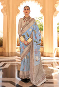 Aqua blue raw silk saree with elegant foliage prints and a classic drape.