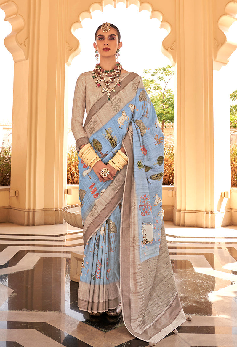 Aqua blue raw silk saree with elegant foliage prints and a classic drape.
