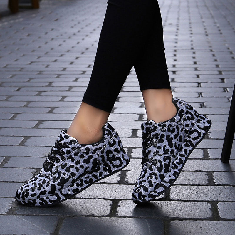 A woman wearing leopard print casual sneakers with black leggings on a paved street. Another image shows the sneakers being held, highlighting the print.