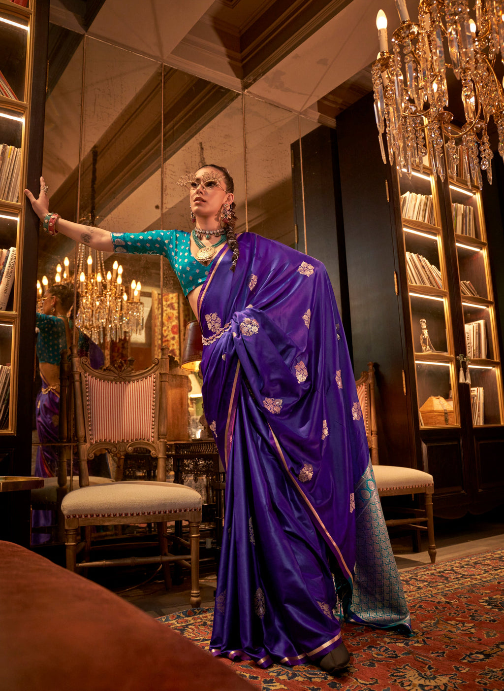 Woman wearing a vibrant teal satin traditional saree with intricate gold geometric weaving for a festive formal event.