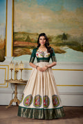 Woman wearing a cream and green Dola silk Kalamkari gown with zari border and matching koti