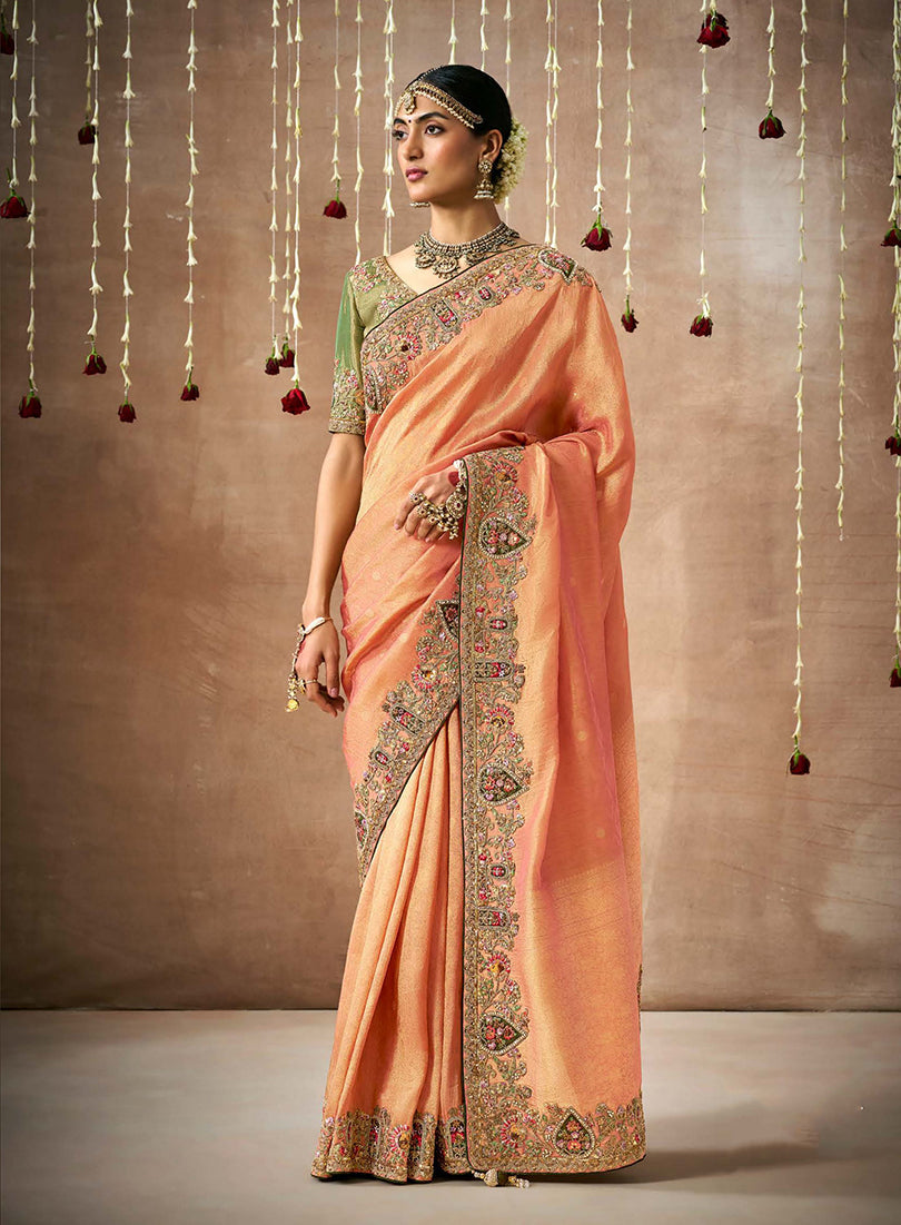 A vibrant orange organza silk designer saree with detailed embroidery.