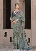 Traditional silk saree featuring geometric patola prints in teal, blue, maroon, and yellow.