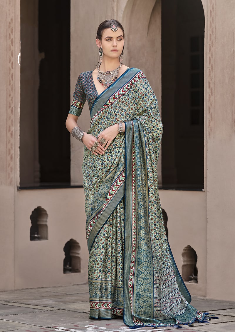 Traditional silk saree featuring geometric patola prints in teal, blue, maroon, and yellow.