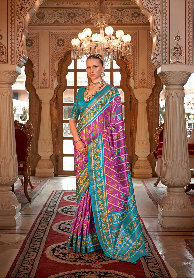 Woman wearing a vibrant violet silk saree with geometric teal and gold patola print for a festive occasion