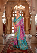 Woman wearing a vibrant violet silk saree with geometric teal and gold patola print for a festive occasion