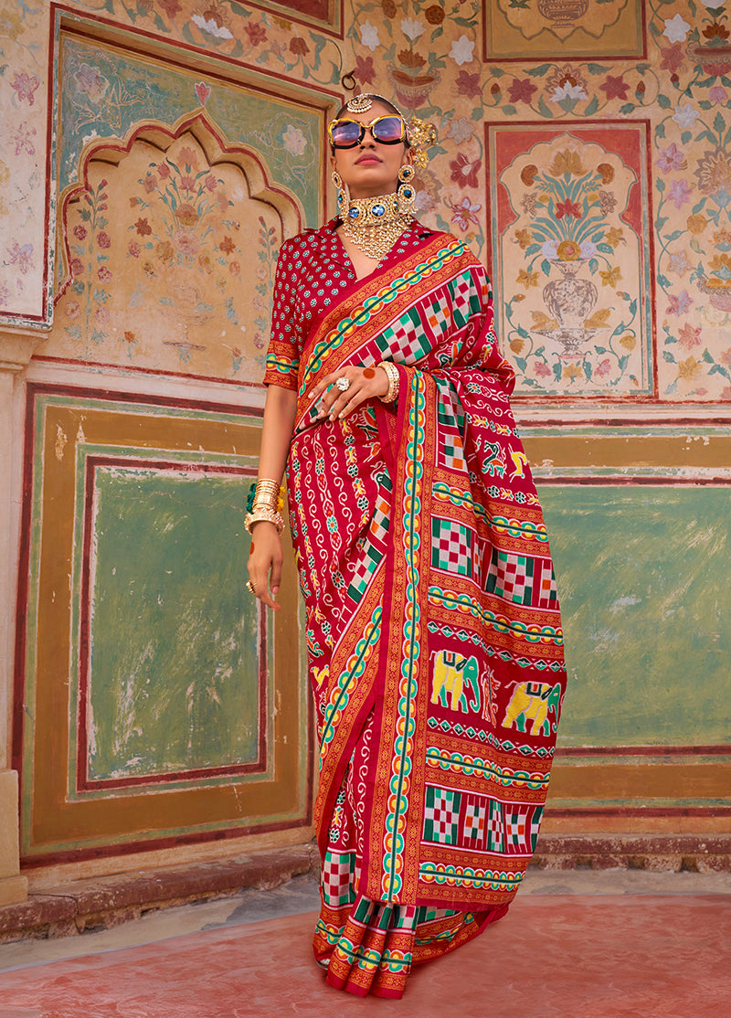 Dark red saree featuring traditional patola print in silk fabric.
