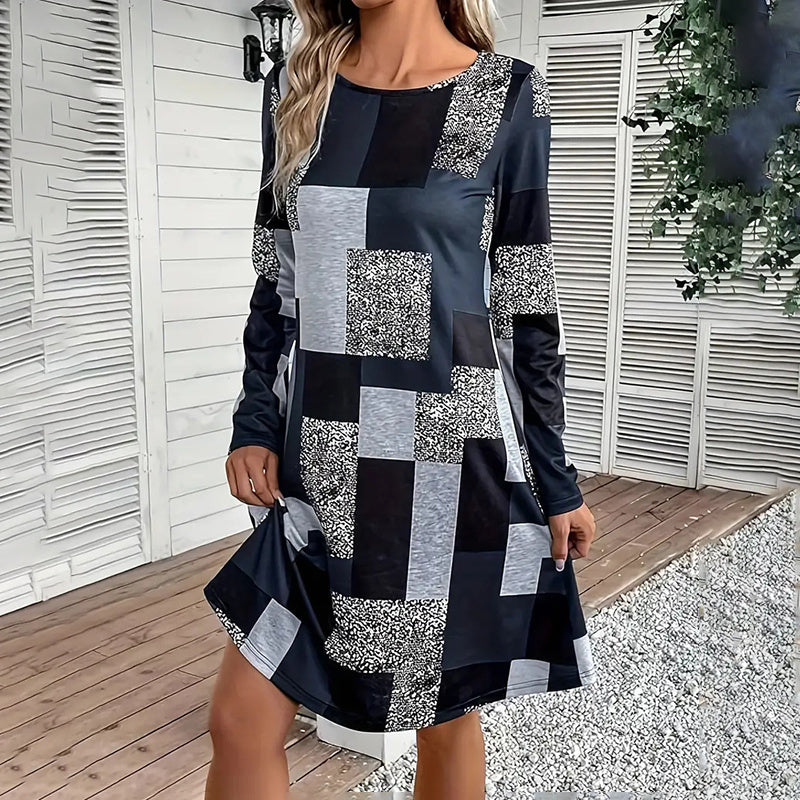 Model wearing a long sleeve round neck dress with a black, grey, and white patchwork digital print design.