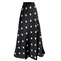 Full-length view of a women's black polka-dot high-waisted A-line maxi skirt with a flowing fishtail hem. Also a lifestyle image of a model wearing a cream polka-dot high-waisted A-line maxi skirt.