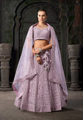 Model wearing a lavender net lehenga choli with detailed thread embroidery.