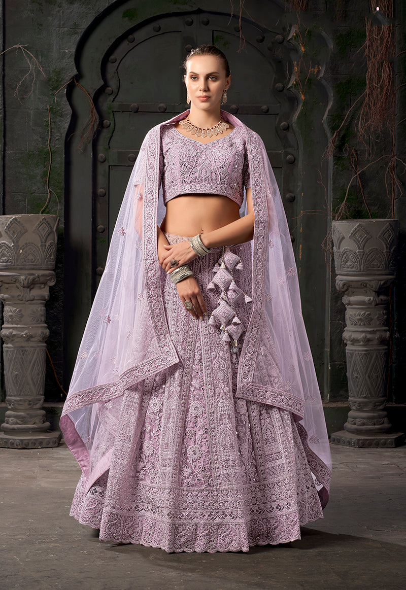 Model wearing a lavender net lehenga choli with detailed thread embroidery.