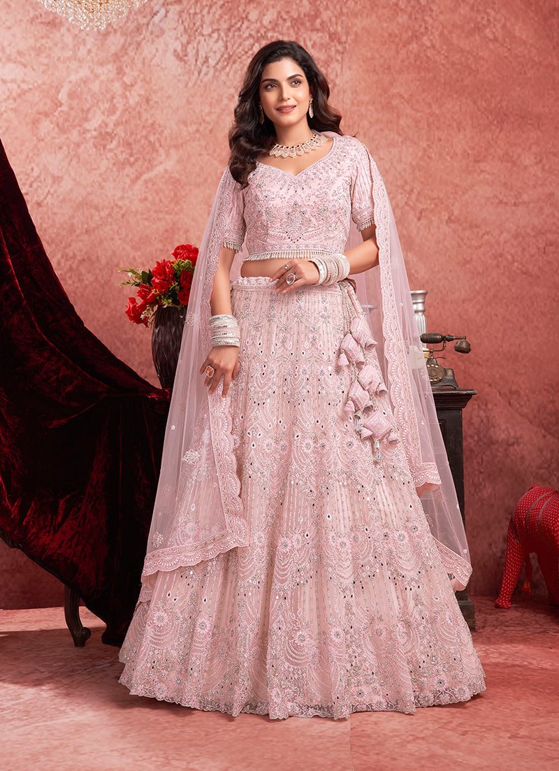 Baby girl wearing a baby pink net lehenga choli with thread embroidery and sequin details.