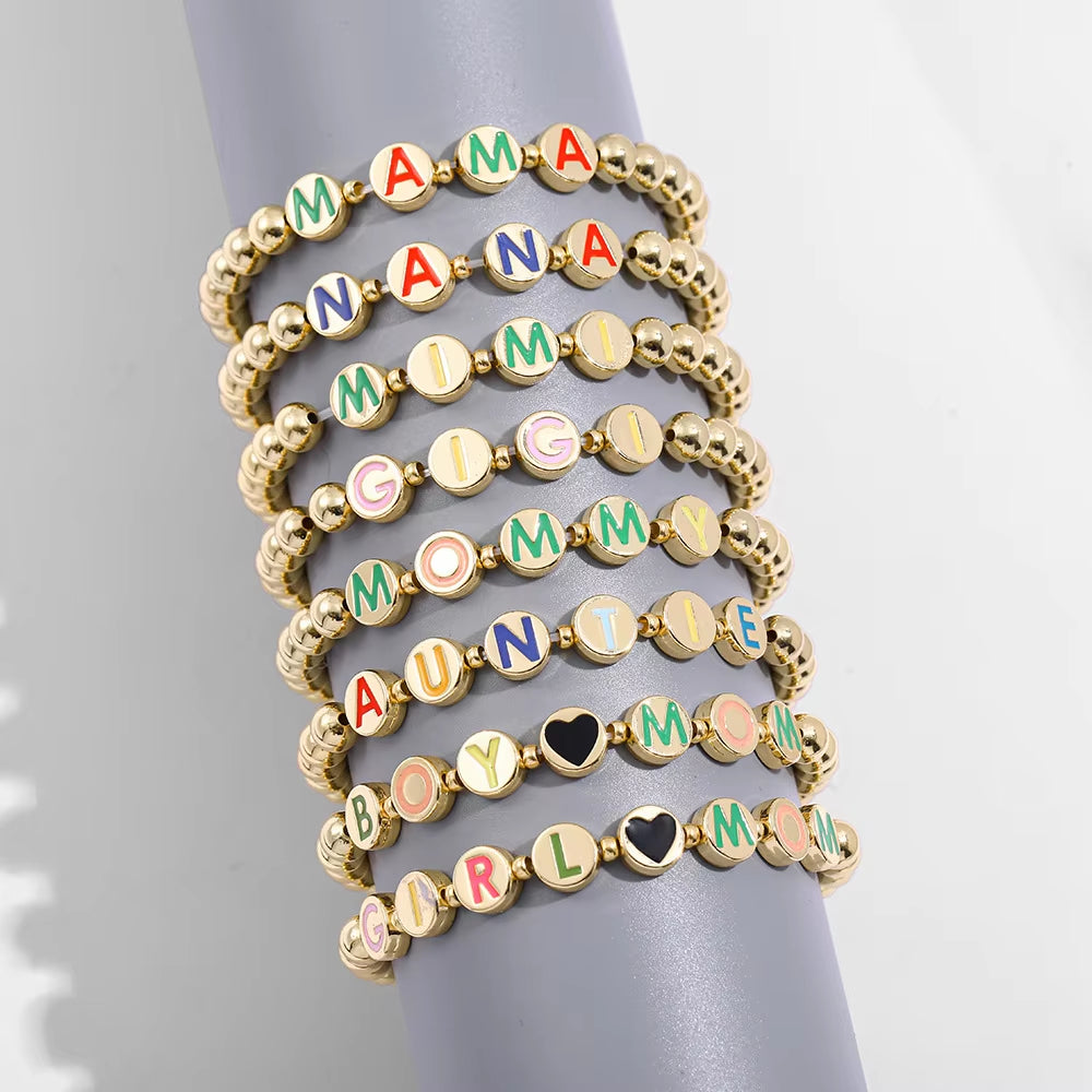 Minimalist gold-plated beaded bracelet with a colorful letter charm on a white background.