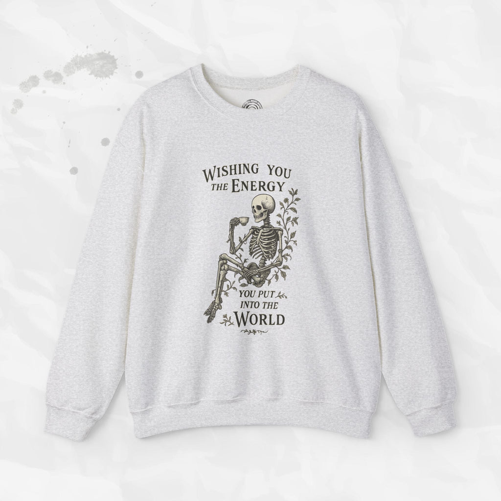 A beige crewneck sweatshirt with a skeleton graphic holding a coffee cup and the text Wishing You the Energy You Put Into the World.