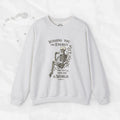 A beige crewneck sweatshirt with a skeleton graphic holding a coffee cup and the text Wishing You the Energy You Put Into the World.