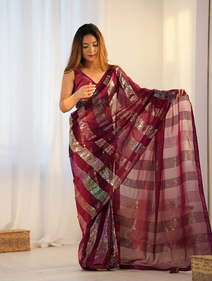 Woman wearing a maroon georgette classic saree with intricate sequin embroidery.