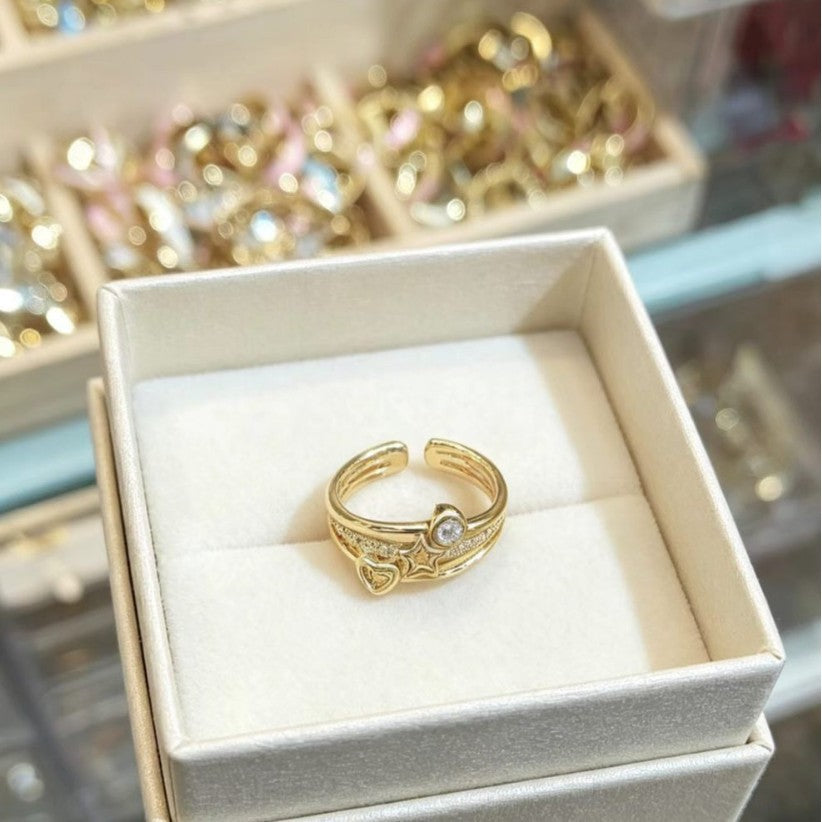 Geometric gold-tone ring with polka-dot and star-inspired diamond-studded details.