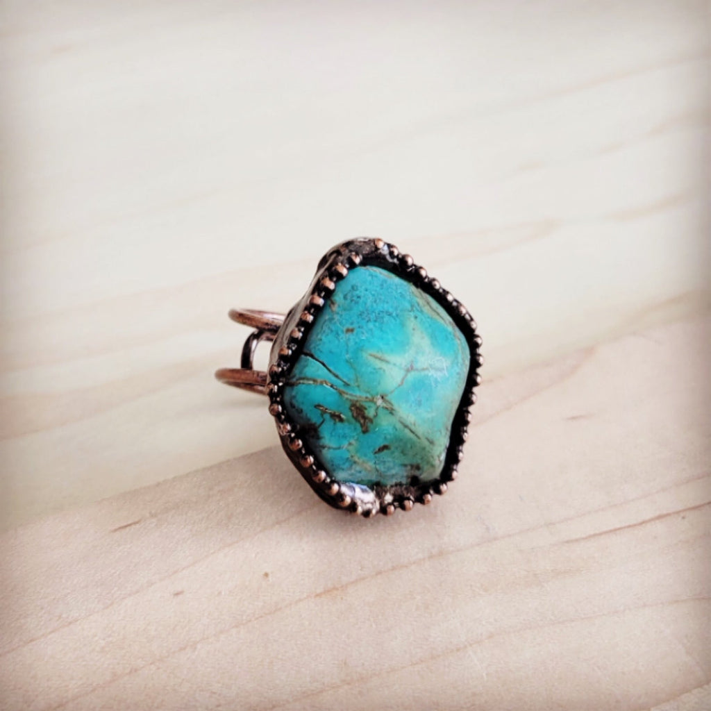 Natural blue turquoise stone set in a dark antique copper ring band on a wooden background