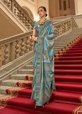 A woman wearing a classic multi-color teal and turquoise satin saree with metallic silver weaving print.