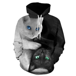 A black and white hooded sweatshirt featuring a large 3D graphic of two cats, one white with blue eyes and one black with green eyes, in a symmetrical design on a white background.