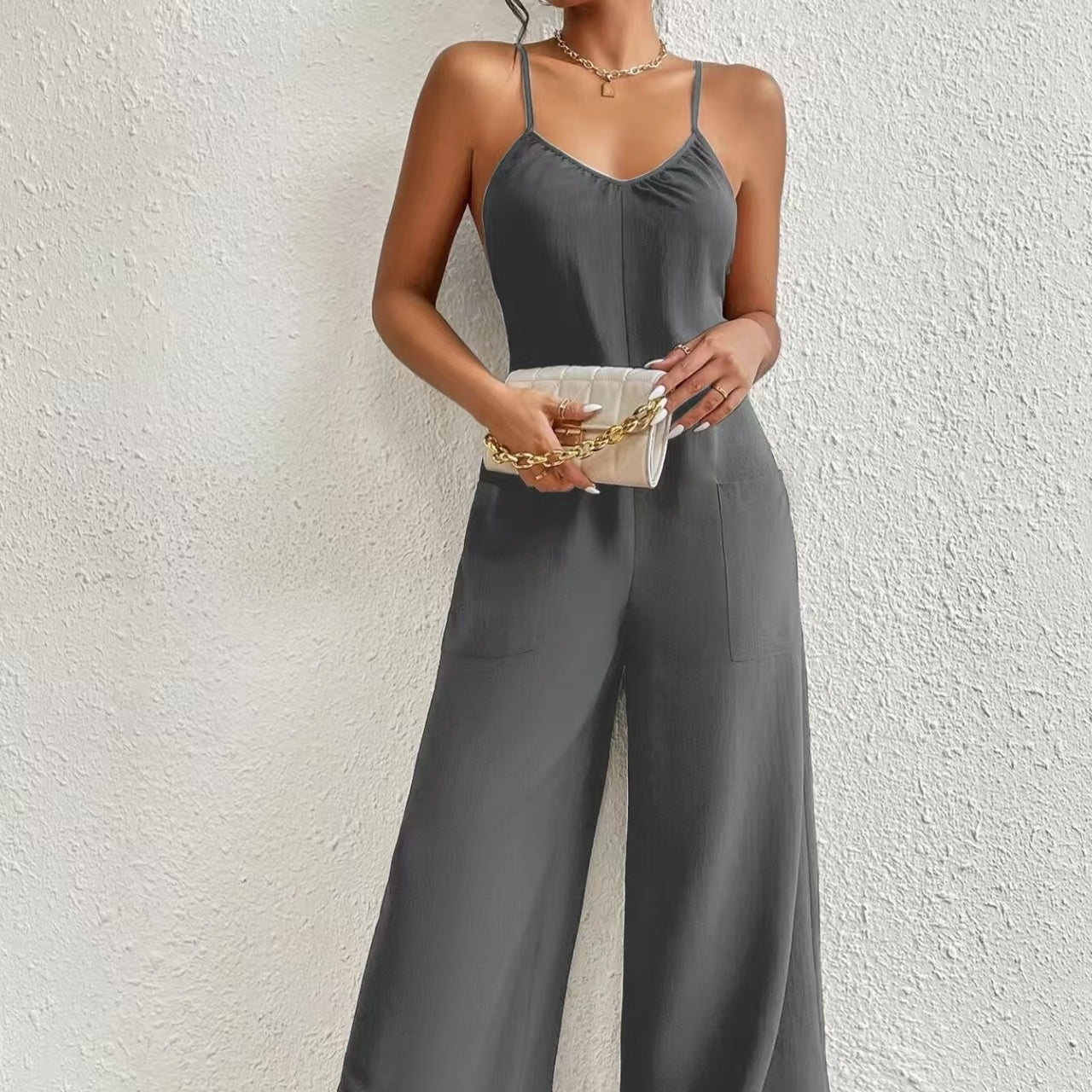 Charcoal grey sleeveless jumpsuit with cross-suspender detail and chest pleats