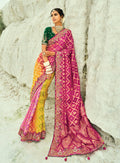 Model wearing a multicolor magenta and yellow silk Bandhej saree with emerald-green accents and embroidery.