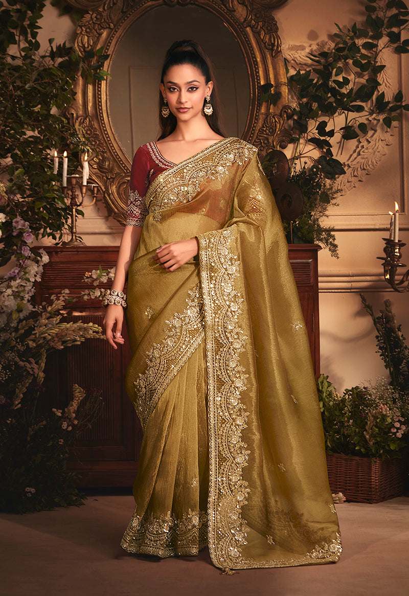 Golden tissue organza saree with all-over butta work and heavy stone-embellished borders.